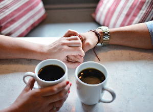 コーヒーを飲みながら手を握り合う二人