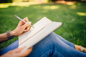 公園でノートに何かを書く女性