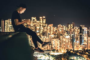 夜景が見える屋上に座っている男性