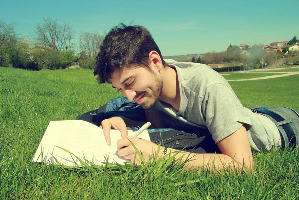 一人で公園で何かを書く笑顔の男性