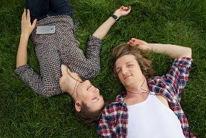 芝生の上で逆さ向きに寝転がるカップル